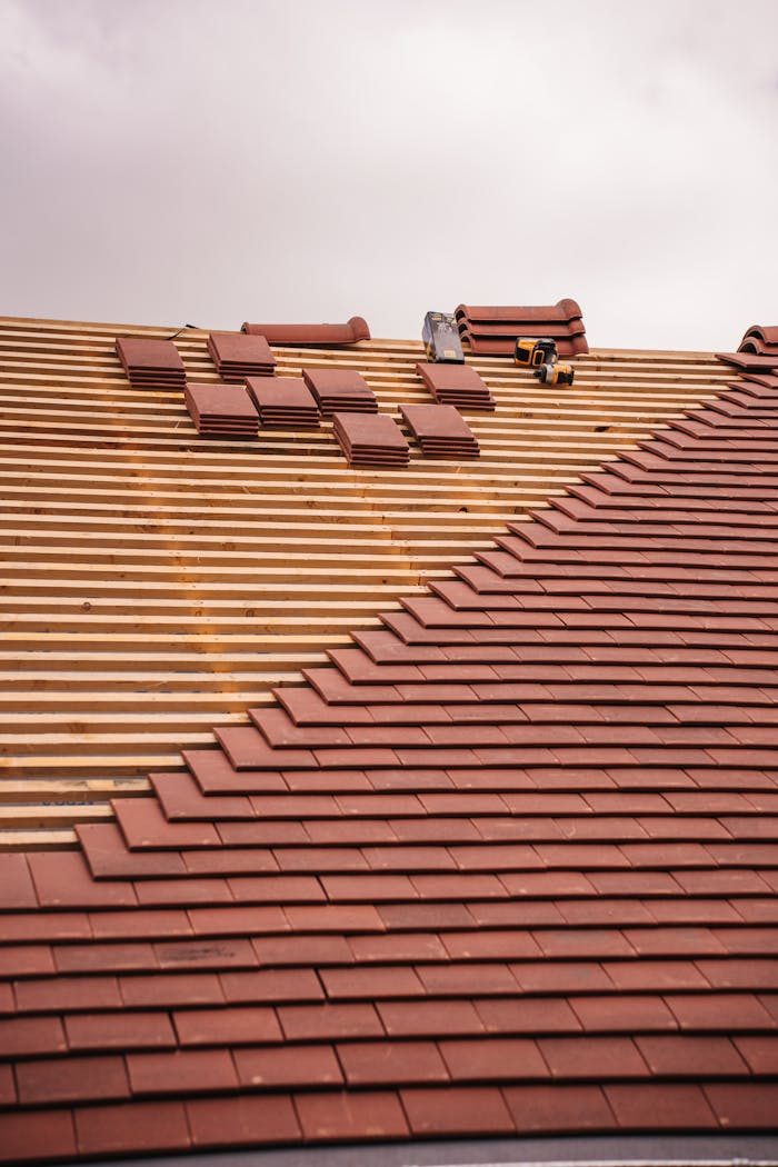Partial installation of a terracotta tile roof on a building in progress.